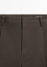 Dunkelbraune, maßgeschneiderte Hose mit Gürtelschlaufen und verdecktem Frontreißverschluss, Markenbezeichnung Massimo Dutti.