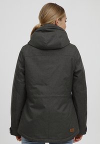 Grijze hoodie-jack met een textuurstof, zichtbare stiksels en een leren accent met merknaam aan de rechter onderzijde.