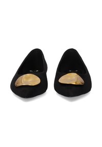 Zapatos planos de ante negros con un gran acento dorado irregular en la zona de los dedos. Tienen una forma redondeada y laterales bajos.