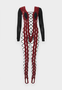 Ολόσωμη φόρμα με μαύρα μακριά μανίκια, λευκά πόδια με μαύρο διασταυρούμενο σχέδιο και έντονες κόκκινες υφασμάτινες κάθετες ρίγες μπροστά και στα πόδια.