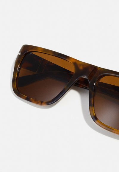 Γυαλιά ηλίου σε ταρταρούγα με χοντρό τετράγωνο σκελετό, καφέ φακούς με τόνωση και ομαλή πλαστική υφή. Χωρίς ορατά στοιχεία ή λογότυπα.