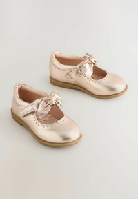 Metalen roségouden Mary Jane-schoenen met een afgeronde neus, een strik aan de voorkant en geperforeerde details op het bovenwerk. Platzool ontwerp.