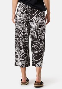 Zwart-witte cropped broeken met een golvend zebra-print ontwerp, voorzien van een elastische tailleband en een lichte stoftextuur.