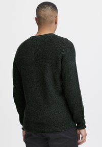 Dark green knitted sweater with a textured pattern, crew neckline, and long sleeves. Features a relaxed fit and ribbed cuffs and hem.