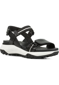 Svart sandal med teksturerte stropper og hvite detaljer. Justerbar spenne, formet fotbed og slitesterk svart gummisåle.