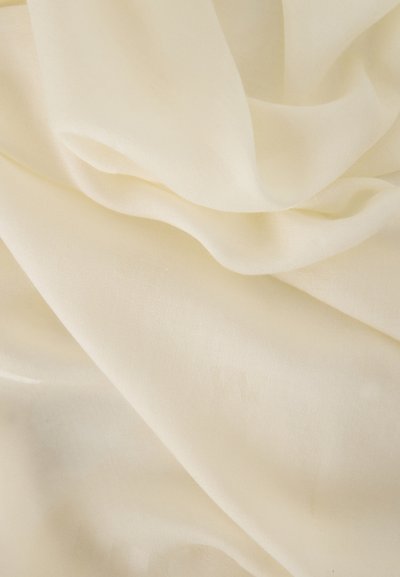 Tissu doux et lisse de couleur crème avec de légères plis et une texture subtile, mettant en valeur son aspect léger et soyeux.