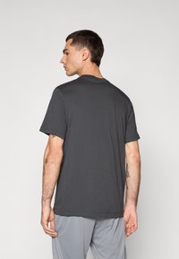 Mørkegrå crew neck t-shirt lavet af bomuld, med korte ærmer og en afslappet pasform, med en glat overflade og et minimalistisk design.