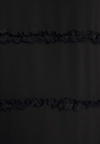 Black fabric featuring horizontal ruffled accents of sheer material. Smooth texture with matte finish, creating contrast with ruffle details.