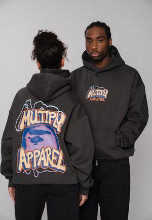 Two people wearing dark hoodies with colorful "Multiply Apparel" logo; one faces forward, the other shows large graphic on back.