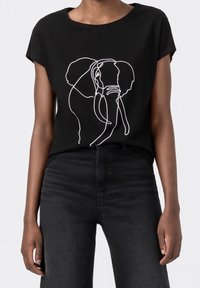 Svart bomull T-shirt med en vit linjeteckning av en elefant. Korta ärmar, avslappnad passform och enkel rund halsringning.