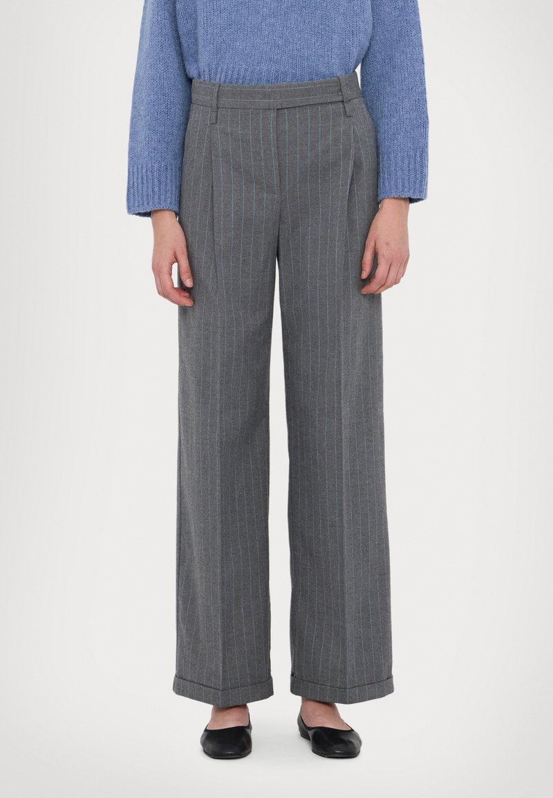Pantaloni larghi grigi con righe verticali blu. Presentano una vita alta e un orlo con risvolto. Il tessuto ha una texture liscia.