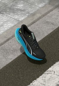 Black running shoe with a perforated upper, silver accents, and a vibrant blue cushioned sole. Features black laces and a logo on the tongue.