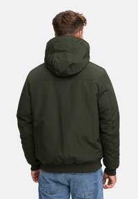 Chaqueta verde con capucha, de textura suave, con dobladillo y puños elásticos; presenta un corte relajado y un diseño minimalista.