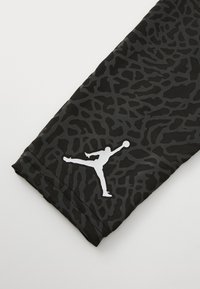Manica da allenamento nera con un motivo testurizzato. Presenta un logo in bianco silhouette nella parte inferiore, realizzata in materiale elasticizzato.