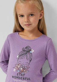 Paarse langwerpige shirt met lange mouwen, voorzien van een afbeelding van een meisje met bloemen, de tekst "STAY WONDERFUL", en een gladde stofstructuur.