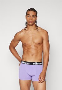 Purple boxer briefs with a black elastic waistband featuring "ellesse" logo. Smooth texture, fitted design, and mid-thigh length.