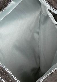 Interno di borsa grigia con una fodera liscia e lucida di colore azzurro chiaro. Presenta una cerniera lungo la parte superiore e una superficie esterna in tessuto testurizzato.