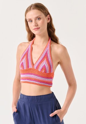 Top corto a halter all'uncinetto con strisce vibranti rosa e arancioni. Presenta una scollatura a V e un corpino aderente. Abbinato a pantaloni navy rilassati.