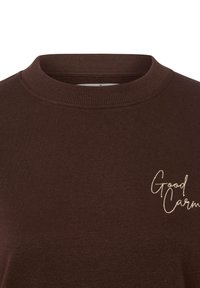 Ciemnobrązowa bawełniana bluza z okrągłym dekoltem, z żeberkowym kołnierzem, z białym haftowanym napisem "Good" i "Carm" po lewej stronie.