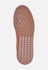 Suola in gomma marrone con un motivo texture, caratterizzata da un accento circolare al centro e bordi curvi. Progettata per aderenza e durata.