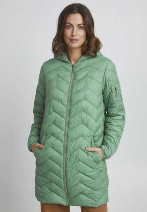 Ljusgrön pufferjacka med ett zigzag-quiltat mönster, framdragkedja, huva och sidofickor, med en slät, glänsande yta.
