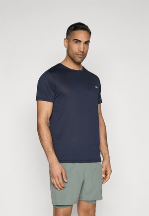 Navyfarbene Sport-T-Shirt mit Rippstruktur, kurzen Ärmeln, Rundhalsausschnitt und kleinem Logo. Kombiniert mit hellgrünen Shorts.