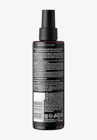 Brun sprayflaska med en svart pump som topp; baksidan har en etikett med detaljerad text på flera språk, streckkoder och produktinformation.