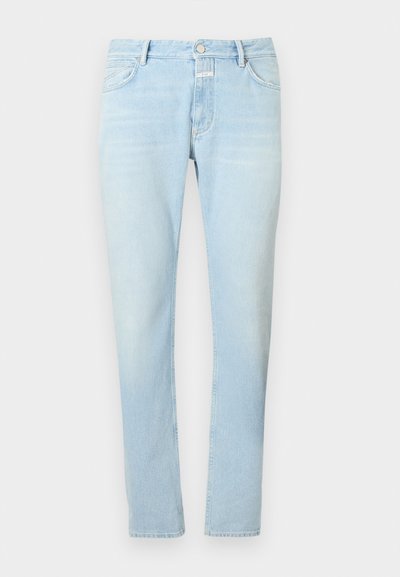 Ανοιχτό μπλε τζιν εφαρμοστό με μπροστινά κουμπιά, φερμουάρ και πέντε τσέπες, ακουμπισμένο επίπεδα σε απλό λευκό φόντο.