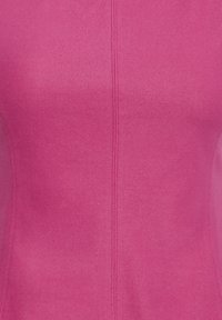 Gros plan sur un tissu rose vif avec une couture verticale au centre, montrant la texture et les détails des points.