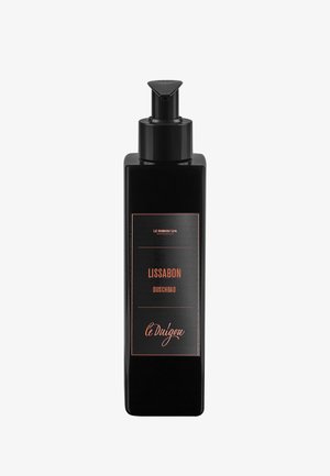 Schwarze rechteckige Spenderflasche mit glänzender Oberfläche, ausgestattet mit einem minimalistischen Etikett, das "Lissabon Duschbad" und "le Dulgau" in Kupfer zeigt.