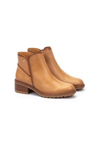 Bottes de cheville en cuir tan avec une texture lisse, bout arrondi et un petit talon carré. Elles présentent des coutures décoratives et une découpe latérale.