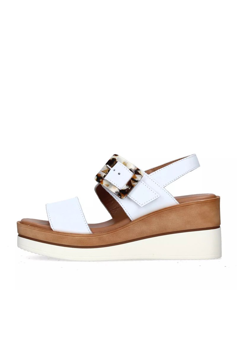 Sandali con zeppa bianchi in pelle liscia, con una grande fibbia in acetato tartarugato e una suola piatta di colore marrone contrastante.