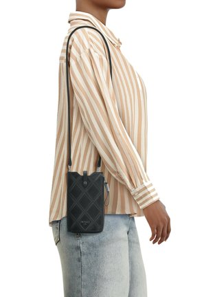Black quilted leather crossbody bag with a sleek rectangular shape, features a top closure and a long strap, viewed at a side angle.