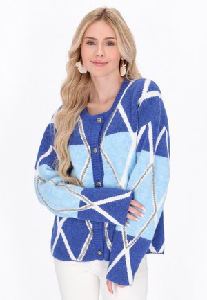 Gebreide cardigan met geometrische patronen in blauw en lichtblauw, met witte en zilverkleurige accenten. Hij heeft een knoopsluiting aan de voorkant en brede mouwen.