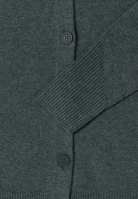 Dunkelgrüner Cardigan aus weichem Strickstoff, mit einem gerippten Bündchen und Saum, ausgestattet mit einem runden schwarzen Knopf an der Vorderseite zum Verschließen.