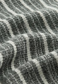 Grau-weißer gestreifter Stoff mit strukturiertem Gewebe, das ein lockeres, offenes Muster und ein weiches Erscheinungsbild aufweist.