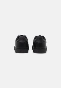 Svarte lær-sneakers med jevn tekstur, rund hæl og gummisåle. Har logo detalj på baksiden. Minimalistisk design.
