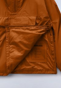 Καφέ μπουφάν με φερμουάρ και υφή στην εξωτερική επιφάνεια, με μεγάλο λογότυπο, εσωτερική ετικέτα φροντίδας και αδιάβροχο, διαπνέον ύφασμα.