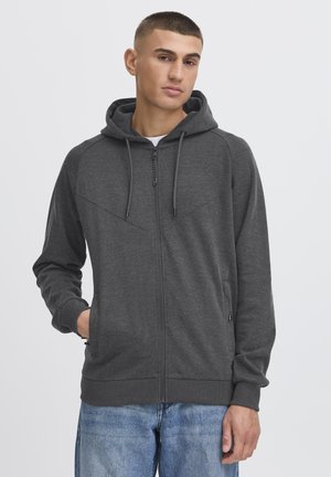 Gray zip-up hoodie with a drawstring hood, two side pockets, and a textured finish. Features angular seam detailing on the front.