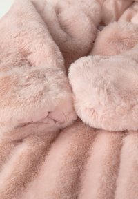Cappotto in pelliccia sintetica rosa con una texture morbida e soffice, caratterizzato da ampi polsini in peluche. Il design include righe verticali per un tocco in più.
