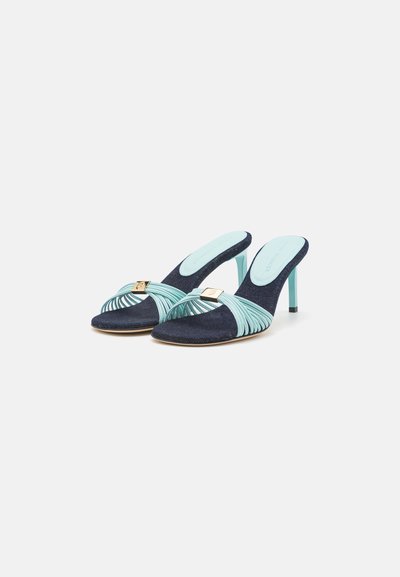 Navy blue high-heeled mules with a textured finish, featuring a mint green braided strap and gold hardware accent.