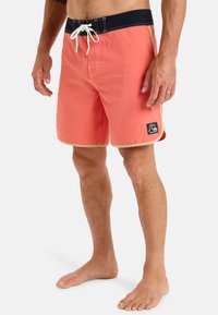 Korálové plavkové šortky s námořnickým pasem, bílým šitím, bočními akcenty a nášivkou s logem. Vyrobeno z lehkého materiálu.