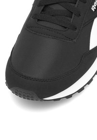 Čierna športová obuv s priedušným nylonovým zvrškom, textúrovanými syntetickými doplnkami, polstrovaným jazykom a gumovou podrážkou s protišmykovým vzorom.