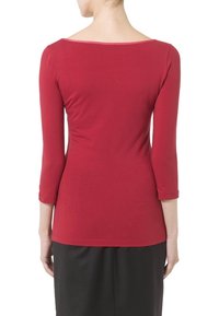 Getailleerde top met lange mouwen in diep rood, gemaakt van gladde stof. Heeft een brede halslijn en een naadloos ontwerp, dat doorloopt tot op de heupen.