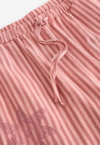 Pantalons rayés rose clair avec taille élastique, cordon de serrage et motif floral brodé en bas à gauche. Texture douce.