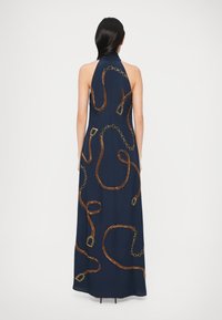 Rochie halter bleumarin cu o siluetă fluidă, având modele cu lanțuri aurii și accente bronzate brodate pe toată suprafața spatelui.