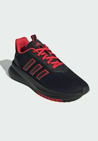 Czarne buty sportowe z czerwonymi akcentami i sznurowadłami, z teksturowanym siateczkowym wierzchem, trzema paskami po bokach oraz amortyzującą podeszwą.