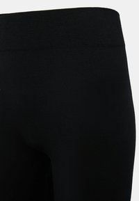 Zwarte leggings van zachte, elastische stof met een brede, elastische tailleband. Gladde textuur zonder zichtbare patronen of hardware.