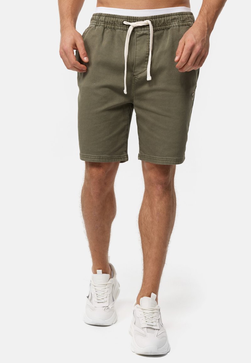 Pantalones cortos de algodón verde oliva con cintura elástica y cordón blanco, con bolsillos laterales y un pequeño detalle de logo en la pierna.