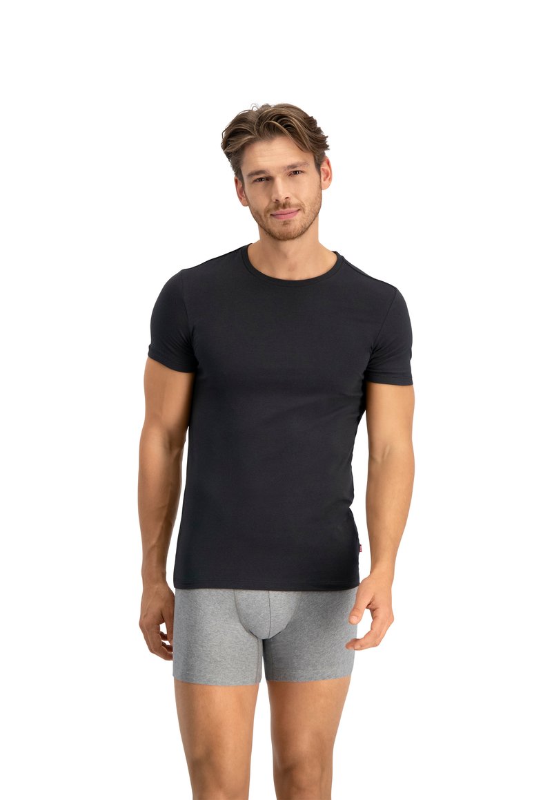 Tricou negru cu mânecă scurtă, confecționat dintr-un material neted, cu un design ajustat și guler rotund. Asociat cu boxeri gri, care au o potrivire strânsă.